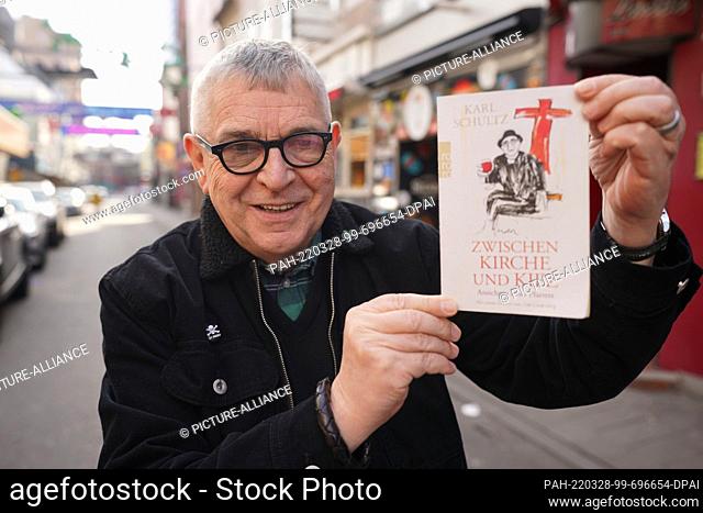 22 March 2022, Hamburg: Pastor Karl Schultz of the St. Joseph Catholic Church holds up his book ""Between Church and Neighborhood"" on the Grosse Freiheit in...