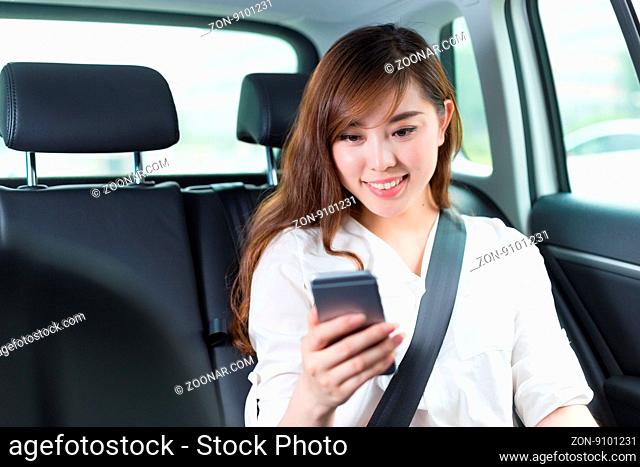 young beautiful asian girl with phone in car