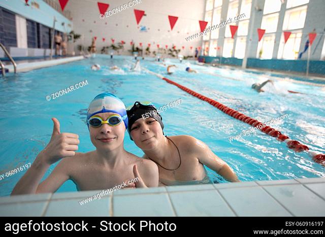 Two boys in swimming caps and goggles in the sports pool