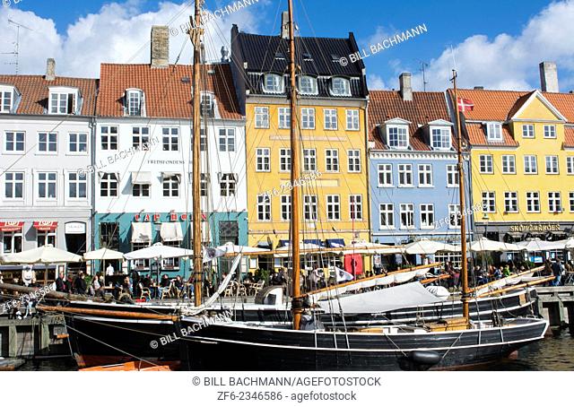 Copenhagen Denmark famous Nyhavn color homes and boats with crowds Kobenhavn tourists