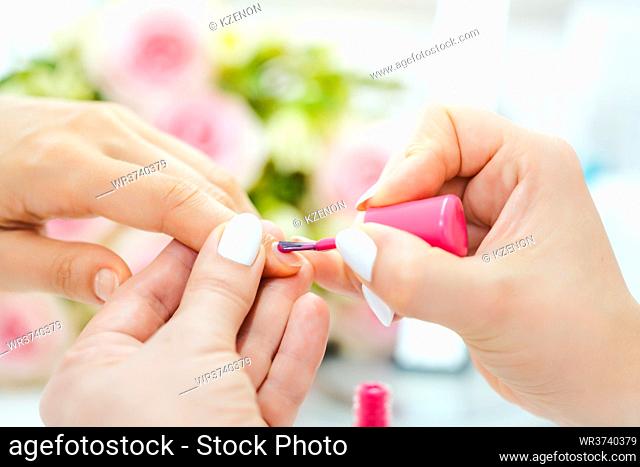 Experienced nail technician applying nail color to fingernails