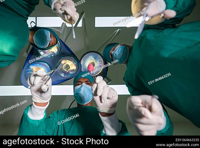 Emergency surgical care concept. Group of surgeons and nurse in surgical green gown uniform performing surgical operation in operating room