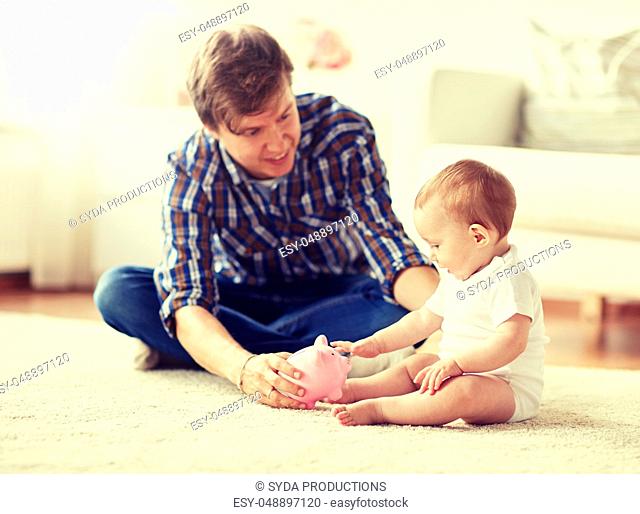 happy father with baby and piggy bank at home