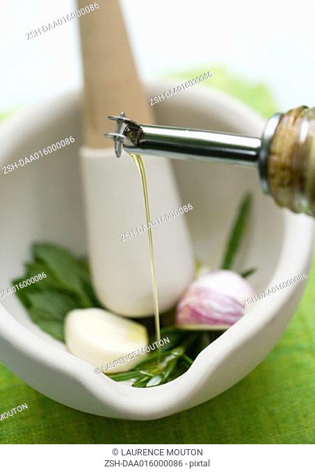 Mortar and pestle with herbs, olive oil and garlic