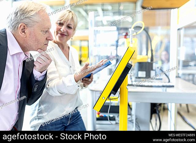 Smiling coworker presenting digital control to senior manager