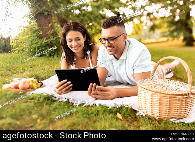 happy couple with tablet pc at picnic in park