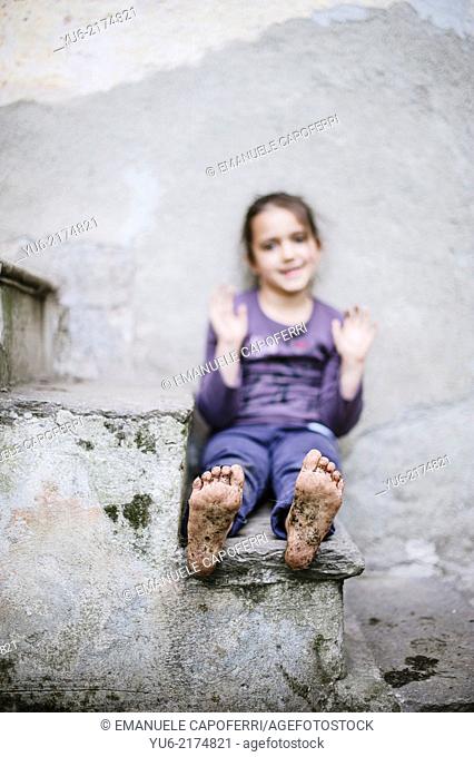 little girl sitting on the stairs with muddy feet