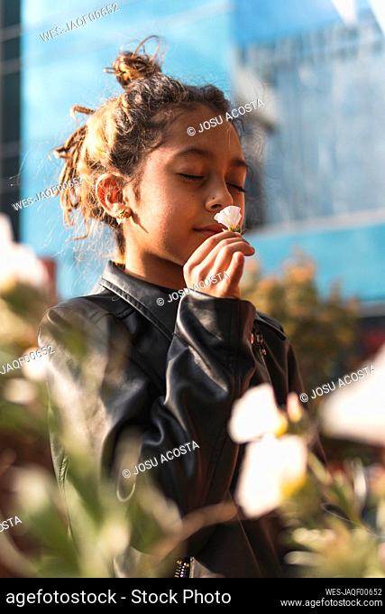 Girl in leather jacket smelling white flower