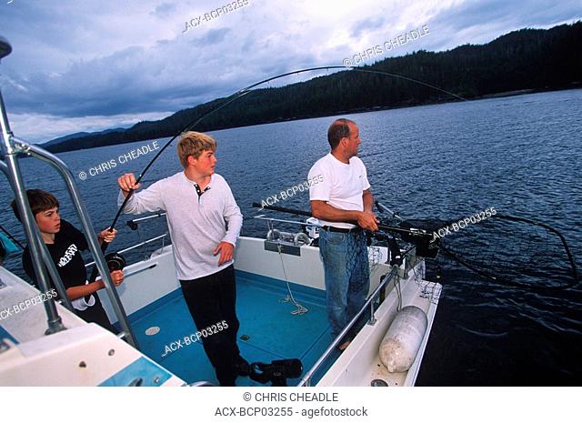 boys plays chinook salmon on fishing boat, Vancouver Island, British Columbia, Canada