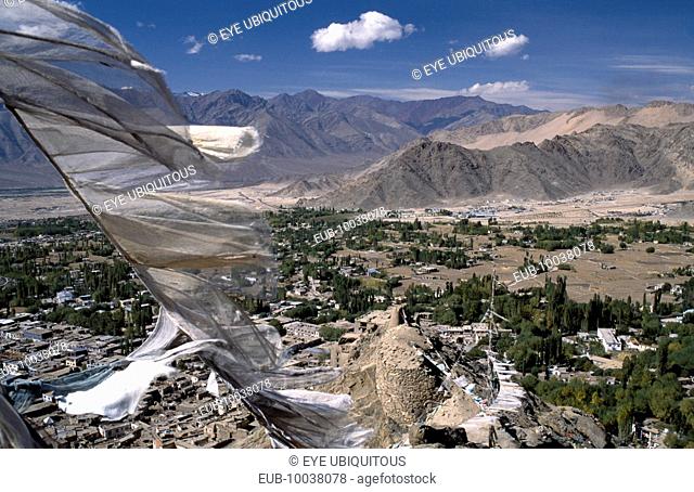 Prayer flags blowing in the wind above village and mountainous terrain