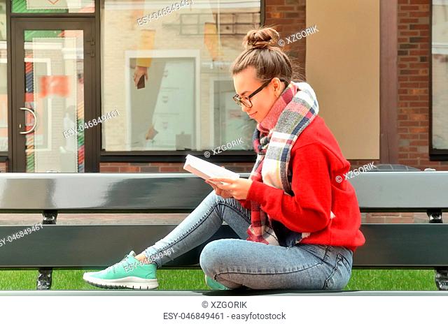 A cute girl in glasses and reading a book
