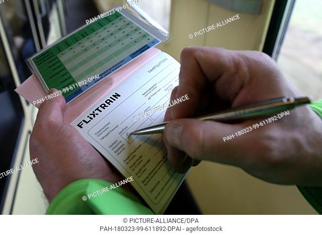 23 March 2018, Germany, Hamburg: A train conductor issues a ticket inside the 'Flixtrain' on its first journey from Hamburg to Cologne