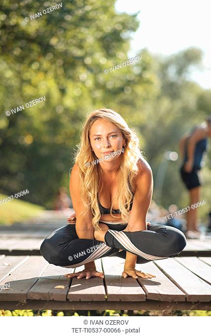 Young woman practicing yoga on boardwalk