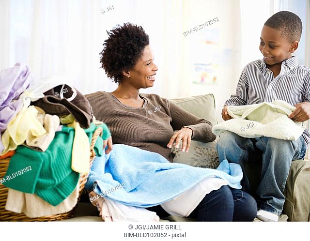 Black mother and son folding laundry