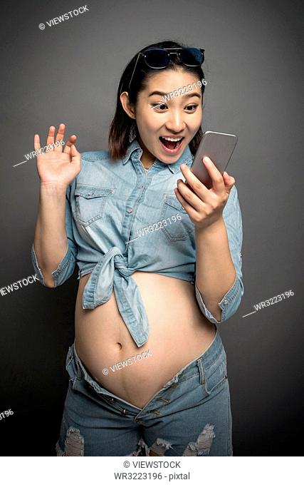 Pregnant women wearing the fashion with a cell phone