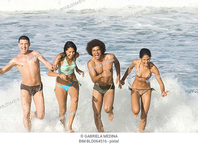 Multi-ethnic friends running in surf at beach