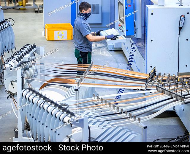 25 November 2020, Mecklenburg-Western Pomerania, Schönberg: Gerber Jan monitors the Flex 1 system for cutting and edging furniture parts in one of the...