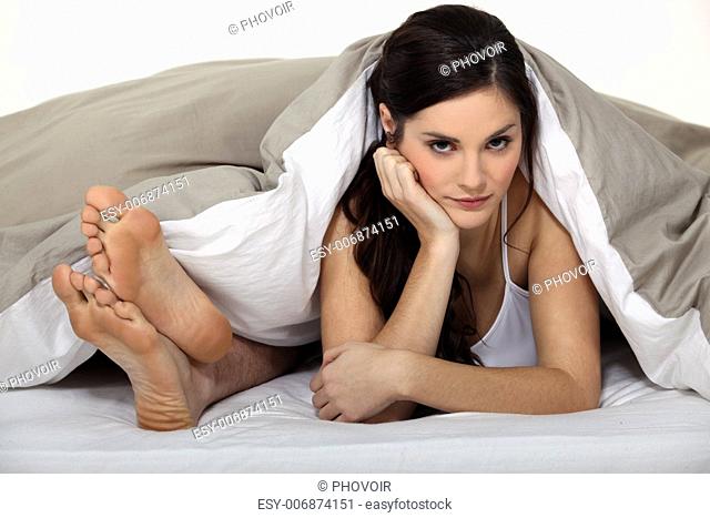 Annoyed woman in bed next to her partner's feet