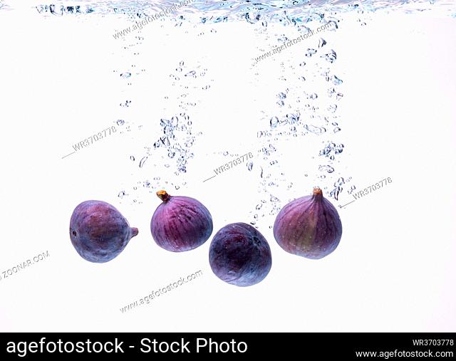 Fresh figs falling into the water isolated on white background. Food photography. Copy space background