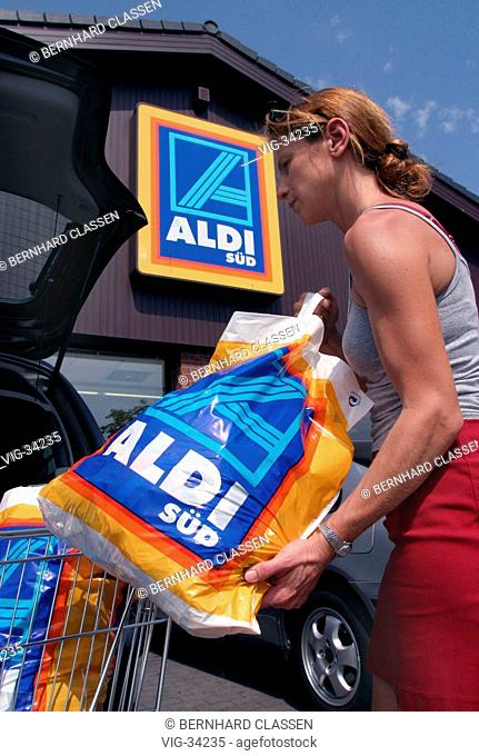 Woman packs her full shopping bags into her car, in front of an Aldi store. - BONN, GERMANY, 16/07/2003