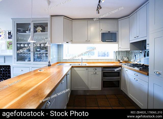 Unit with wooden worktop in kitchen with blue painted fitted units