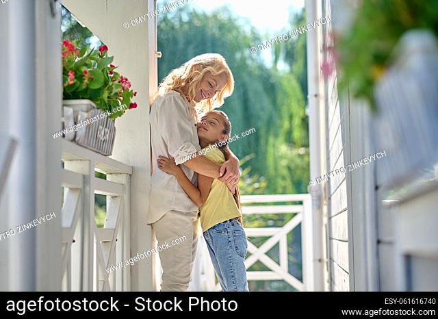Family. Blonde mid aged woman hugging a cute girl