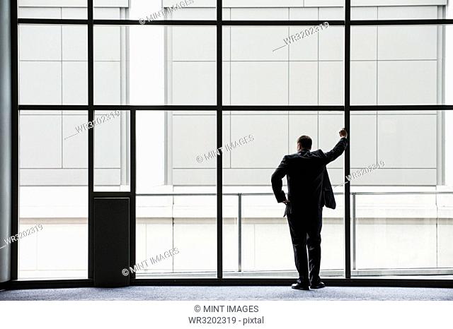 A businessman in silhouette standing at a large window in a convention centre lobby