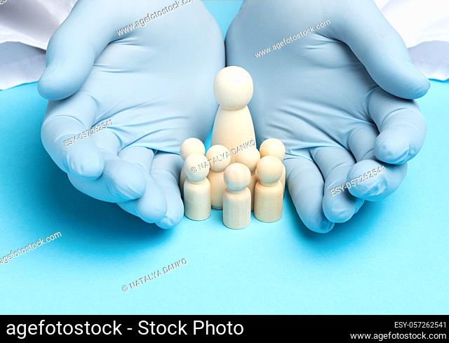 two male hands in blue latex gloves and wooden figurines of a woman with children, the concept of a large family and insurance