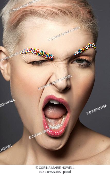 Young woman with sprinkles on eyebrows, winking