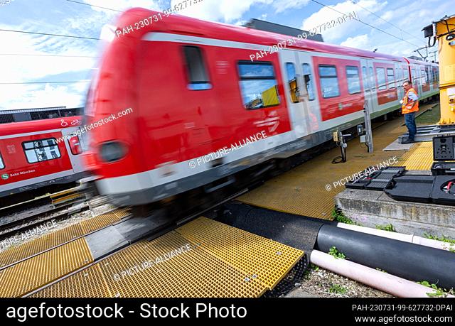 31 July 2023, Bavaria, Munich: A commuter train passes through a digitized wheelset measuring system at the Munich-Steinhausen commuter rail plant during a...