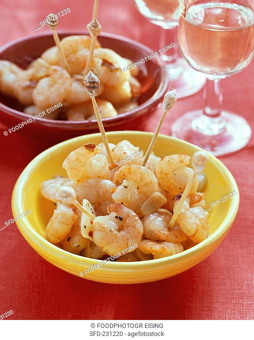 Garlic shrimps with cocktail sticks in bowls, white wine