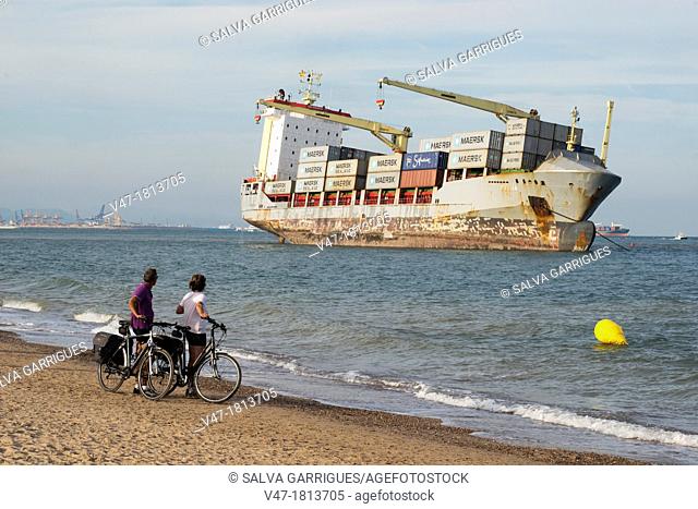 Cyclists looking the boat beached on the sand, El Saler, Valencia, Spain, Europe