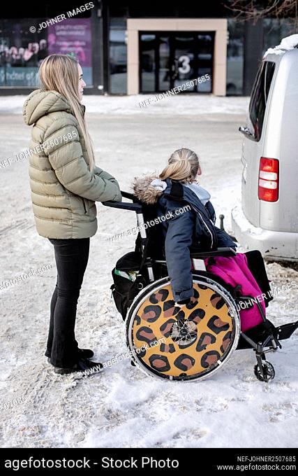 Woman pushing girl on wheelchair