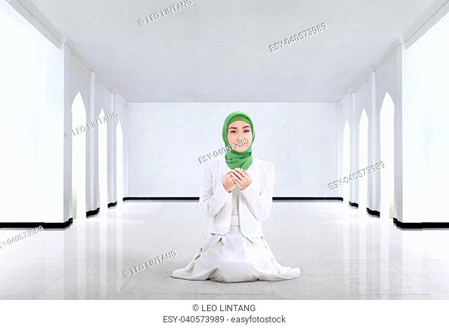 Pretty asian muslim woman praying to god in the mosque