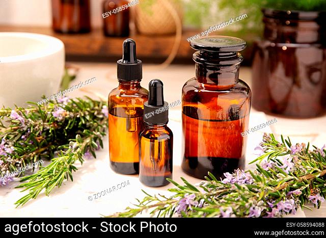 Rosemary essential oil on vintage apothecary bottles. Herbal oil for skin care, aromatherapy and natural medicine