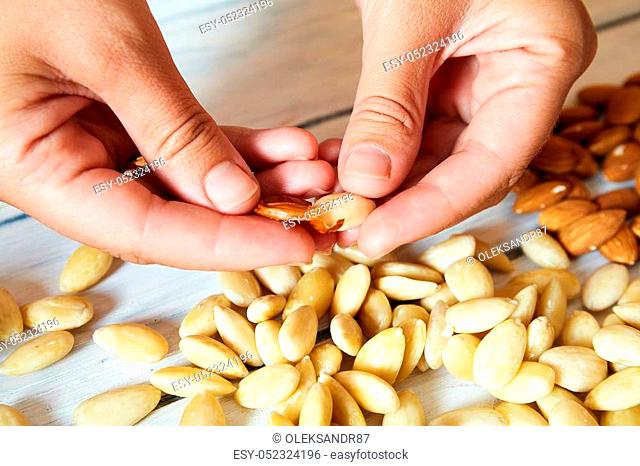 peeled almonds with hand on the table. almond meal