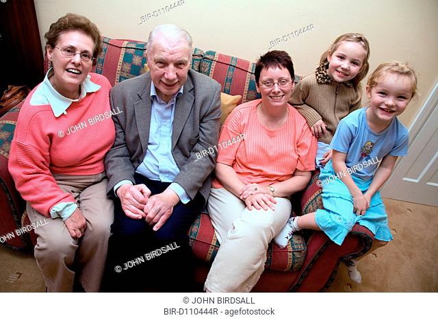 Older couple with their daughter and grandchildren sitting on the sofa