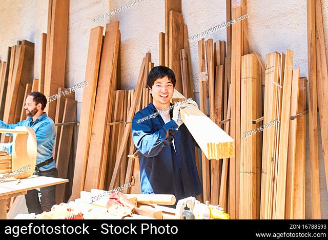 Arbeiter oder Handwerker Lehrling beim Holz tragen im Holzlager der Tischlerei