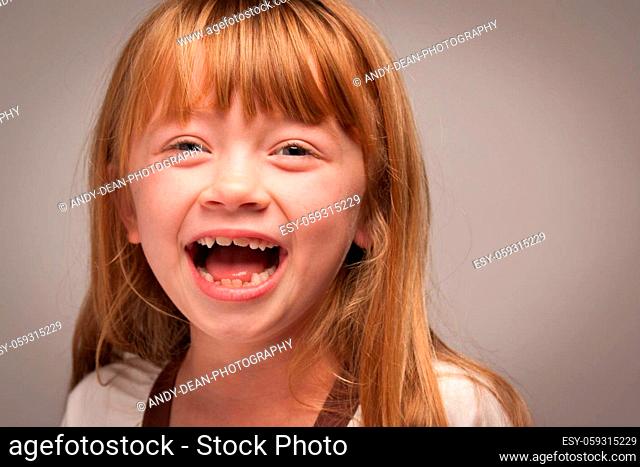 Fun Portrait of an Adorable Red Haired Girl on a Grey Background