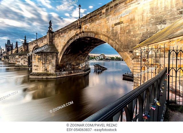 A view through the arch of Charles Bridge at sunrise, in the background Old Town and the National Theater