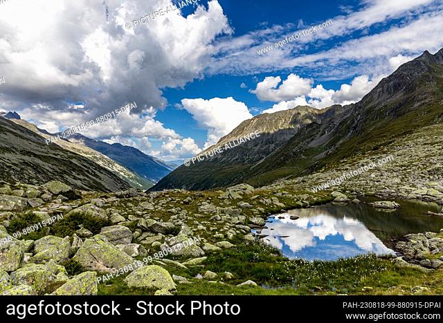 17 August 2023, Austria, -: Clouds are reflected in a collection of water on a hiking trail between Tyrol (Austria) and South Tyrol (Italy)
