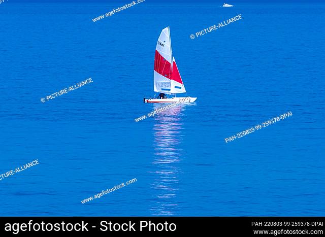 03 August 2022, Mecklenburg-Western Pomerania, Ahrenshoop: A sailboat is underway on the almost glassy waters of the Baltic Sea