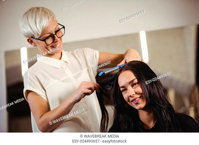 Female hairdresser straightening the hair of a client