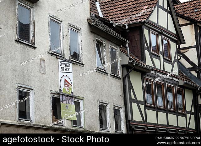 PRODUCTION - 05 May 2023, Lower Saxony, Hann. Münden: The old facade with a poster ""Get involved!"" makes a residential building purchased by...