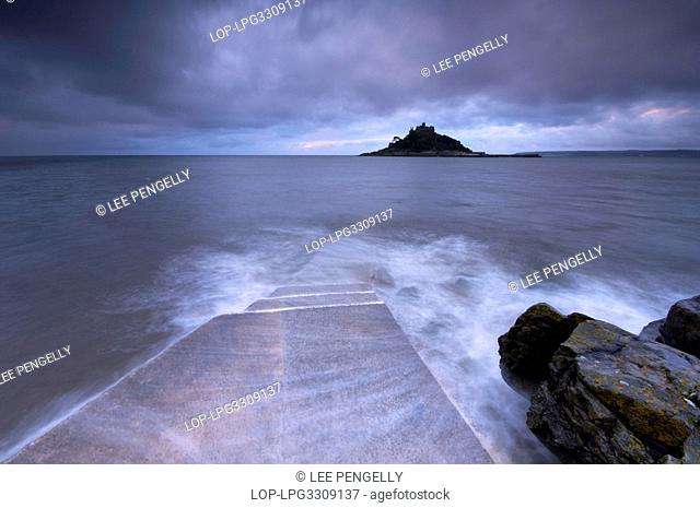England, Cornwall, Marazion, The dawn tide washing over the man-made causeway that links St Michael's Mount to Marizion beneath stormy skies