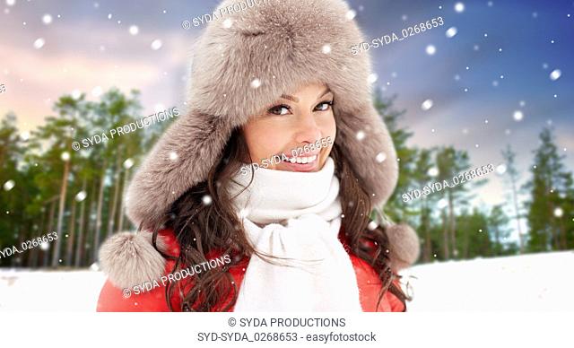 happy woman in fur hat over winter forest