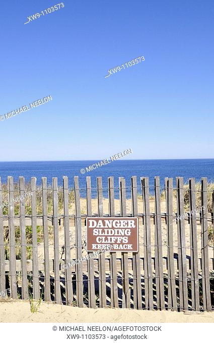 Beach fence and warning sign at edge of cliff to ocean on Cape Cod National Seashore, Nauset Light Beach, Eastham