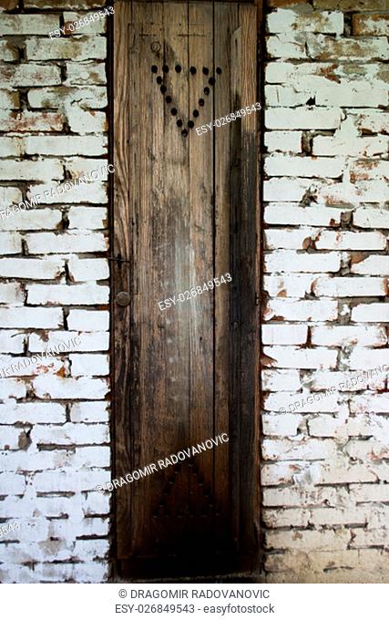 Rustic smokehouse door on white brick wall