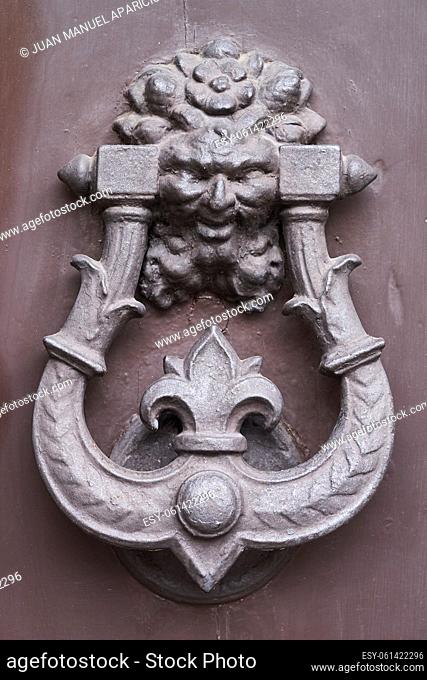 Old wrought iron knocker on a wooden door