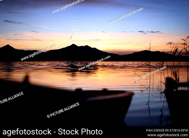 28 September 2023, Bavaria, Füssen: Rowing boats lie in the sunset on the shore of the Hopfensee, located on the edge of the Alps